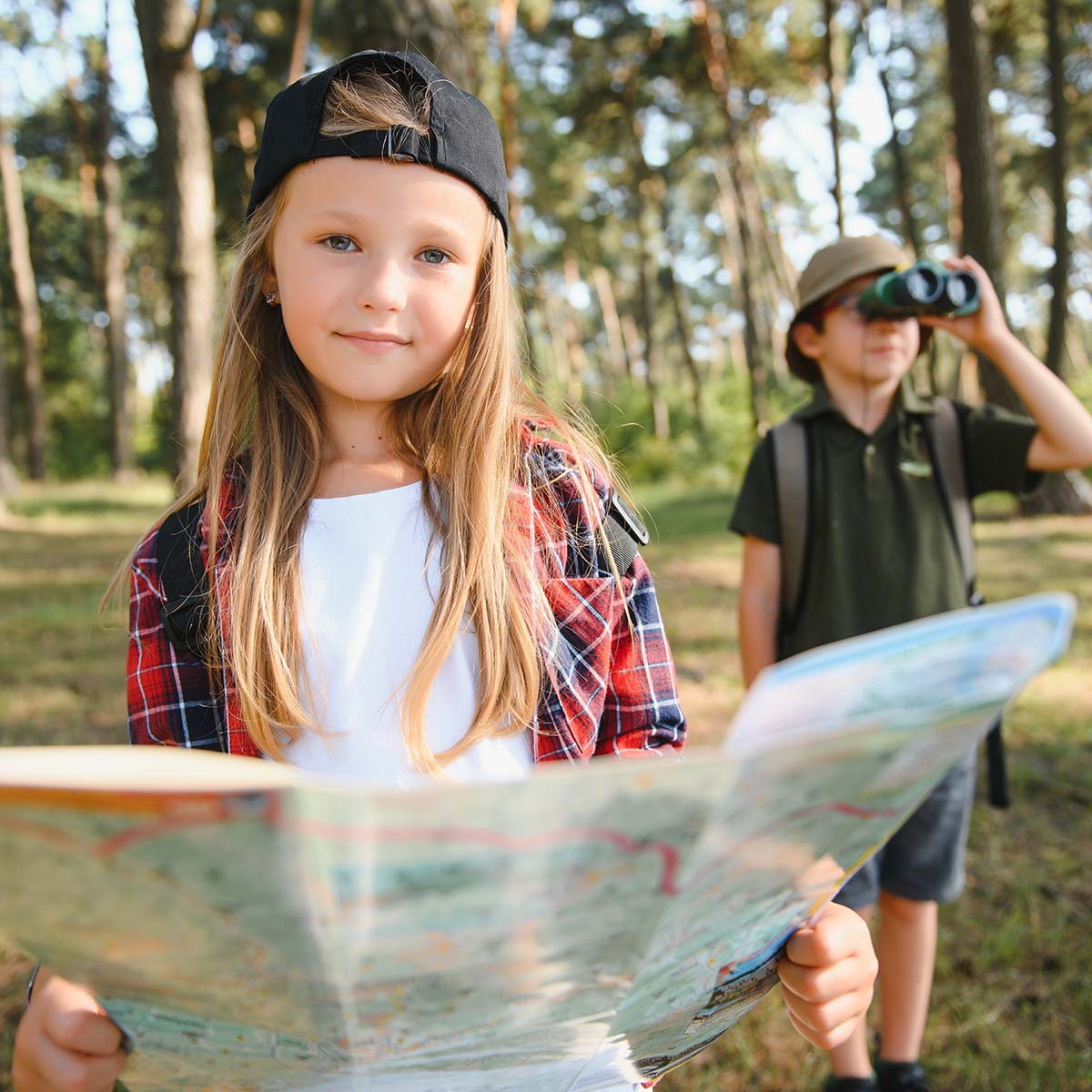 Deti hrajú hru v areáli Sojka resortu s mapou v ruke a hľadajú poklad.